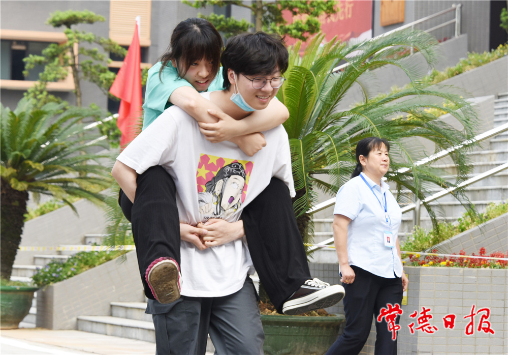 6月8日，普通高等學(xué)校招生全國統(tǒng)一考試湖南省澧縣第二中學(xué)考點，一名男考生背著腳部受傷的女考生走向考場。             柏依樸  何祖華 攝.jpg